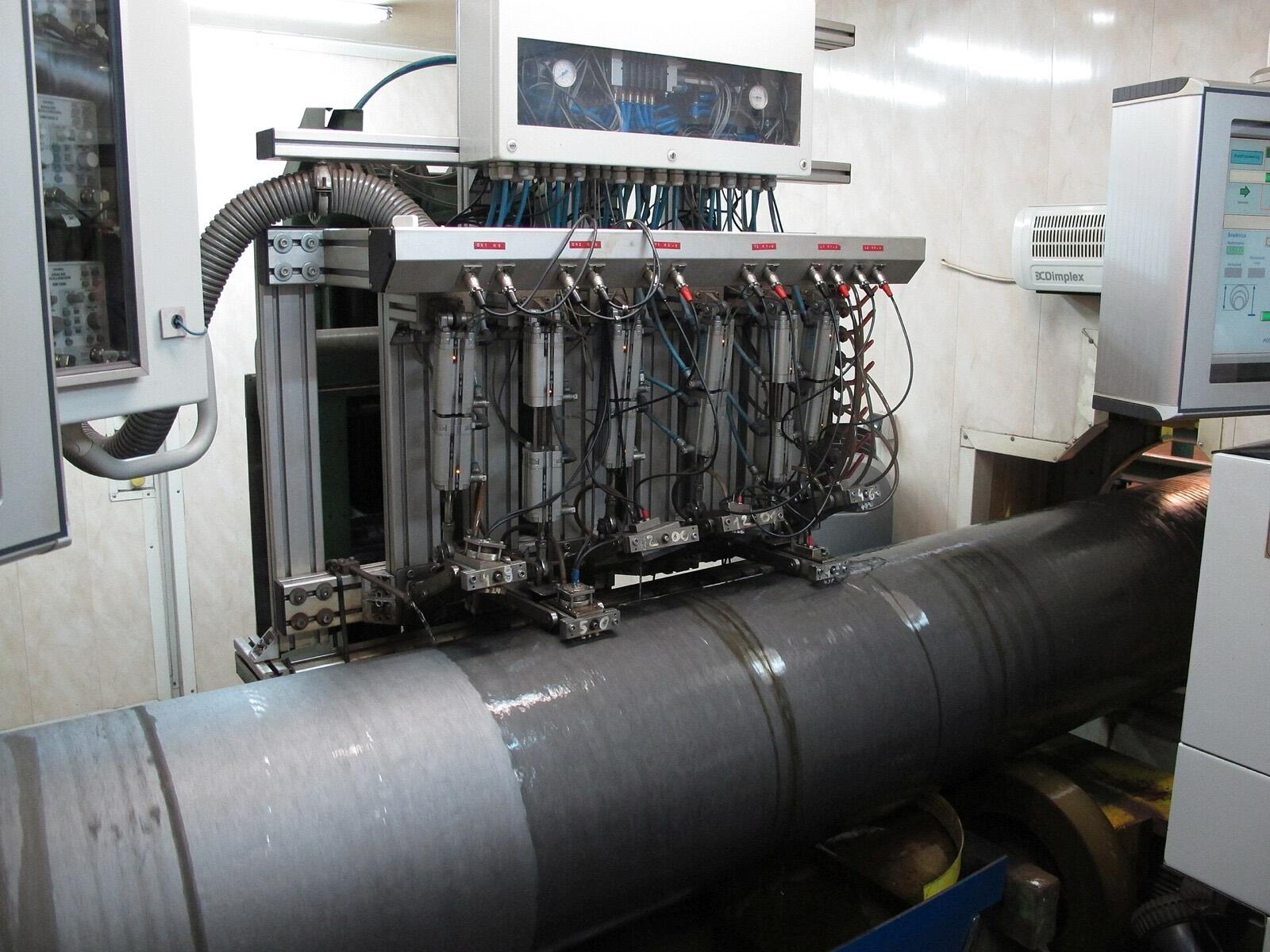 Automated ultrasonic testing rig scanning a steel pipe