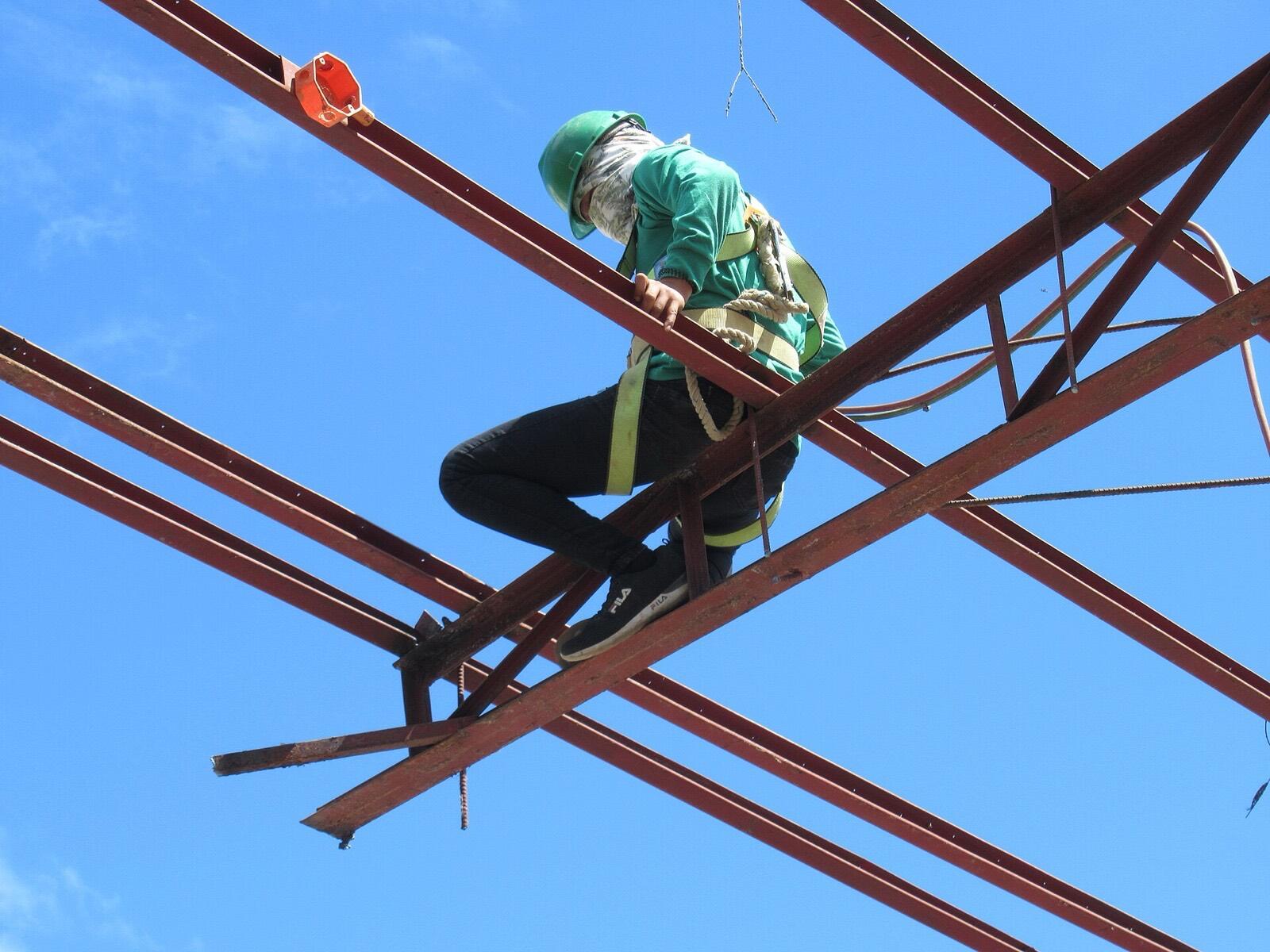 Ironworker in a harness bolting a steel truss